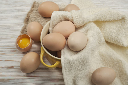 Bowl of raw chicken eggs on the wooden background