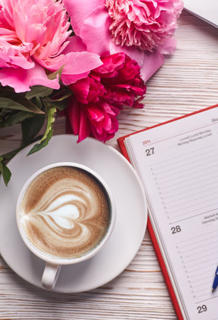 Morning coffee mug for breakfast, empty notebook, pencil and pink peony flowersの写真素材