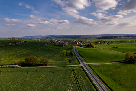 Village surrounded by beautiful hilly green landscape at a colorful sunrise, aerial footageの写真素材