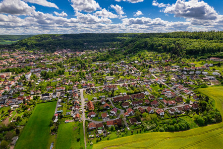 Top view of a field of yellow flowers with a small town in the background. The sky is cloudy and the sun is shining through the clouds. Germany.の写真素材