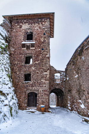 A castle with a snow covered roof and a steeple. The castle is surrounded by a snowy landscape. Ruin of Hohnstein Castle, Harz mountains, Germany.の写真素材