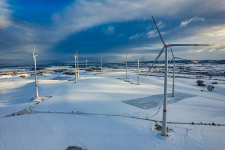 Drone shot of wind turbines in late afternoon light in flat snowy northern German landscapeの写真素材