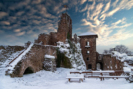 A castle with a snow covered roof and a steeple. The castle is surrounded by a snowy landscape. Ruin of Hohnstein Castle, Harz mountains, Germany.の写真素材