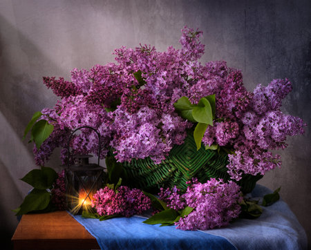 A beautiful arrangement of lilac flowers is displayed in a white vase on a table. The flowers are in full bloom and their vibrant color creates a sense of freshness and vitality.の写真素材