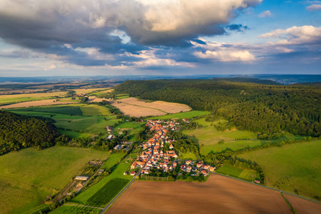 Vibrant German Village Nestled in a Valley Surrounded by Lush Greenery and Picturesque Mountains on a Bright Sunny Dayの写真素材