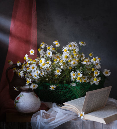 A cheerful collection of daisies in a vintage jug, with an open book, creating a charming sceneの写真素材