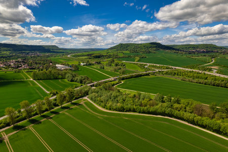 This stunning aerial photograph beautifully depicts lush green fields contrasted against a dramatic, cloudy skyの写真素材