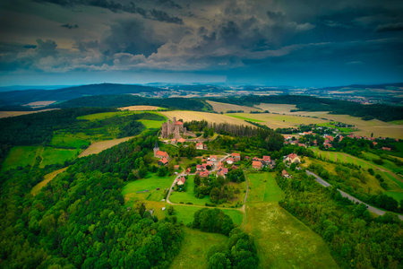 A stunning aerial capture of a historic castle nestled elegantly amidst lush green fields and...