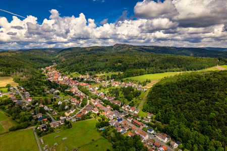 Charming german sprawling villages across a lush valley, with vibrant rooftops dotting the landscape under a blue sky adorned with fluffy clouds. Nature thrives in every direction. Germany.の写真素材
