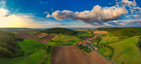 Charming german sprawling villages across a lush valley, with vibrant rooftops dotting the landscape under a blue sky adorned with fluffy clouds. Nature thrives in every direction. Germany.の写真素材