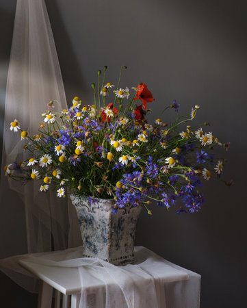 A beautifully arranged bouquet of vibrant wildflowers positioned beside an elegant tea cup and an open bookの写真素材