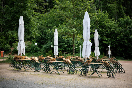 Charming outdoor caf with wooden tables and umbrellas surrounded by greeneryの写真素材
