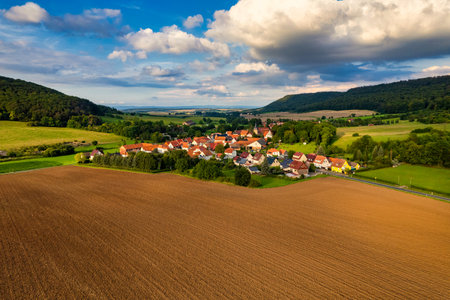 Charming german sprawling villages across a lush valley, with vibrant rooftops dotting the landscape under a blue sky adorned with fluffy clouds. Nature thrives in every direction. Germany.の写真素材