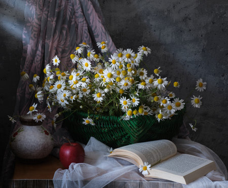 A cheerful collection of daisies in a vintage basket, with a red apple and an open book, creating a charming sceneの写真素材