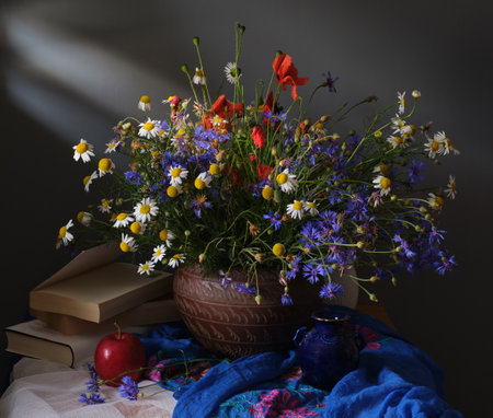 A beautifully arranged bouquet of vibrant wildflowers positioned beside an elegant tea cup and an open bookの写真素材