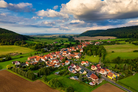 Charming german sprawling villages across a lush valley, with vibrant rooftops dotting the landscape under a blue sky adorned with fluffy clouds. Nature thrives in every direction. Germany.の写真素材
