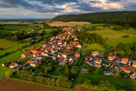 Vibrant German Village Nestled in a Valley Surrounded by Lush Greenery and Picturesque Mountains on a Bright Sunny Dayの写真素材