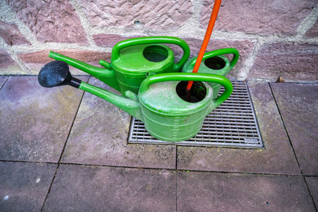 Plastic garden sprinklers standing against a stone wall. A country concept.の写真素材