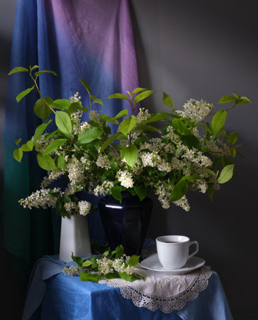 A tranquil still life composition showcasing a delicate tea cup and a vibrant lush floral arrangementの写真素材