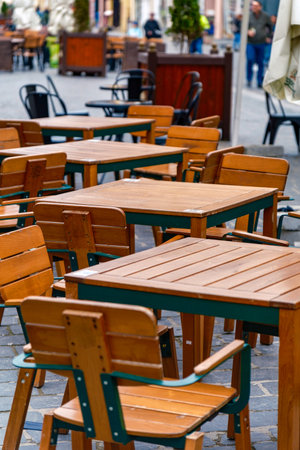 Outdoor cafe with empty wooden tables and chairs on the patio. Inviting relaxation and leisurely moments.の写真素材