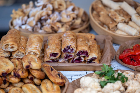 Assorted savory and sweet pastries lined on wooden stall, golden-brown rolls, strudels and filled puffsの写真素材