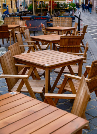 Outdoor cafe with empty wooden tables and chairs on the patio. Inviting relaxation and leisurely...