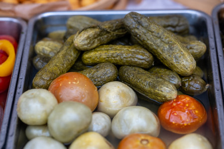 Tray of pickles onions tomatoes glistening with brine, rustic market display offering crunchy tangy preservedの写真素材