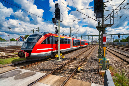 Modern train arriving at platform midday, dynamic commuter scene with clear motion lines, overhead...