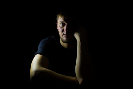 The guys face on a dark background, with an isolated light.の写真素材