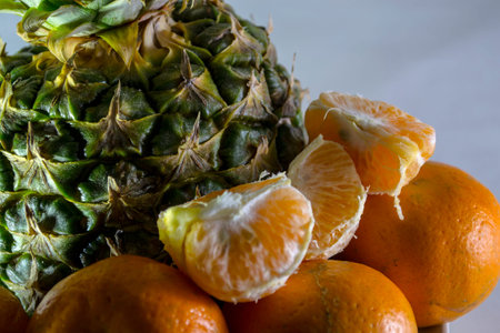 Pineapple and tangerines on a white plate close-up.の写真素材