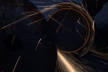 Sawing a metal pipe with an electric saw. Sparks fly