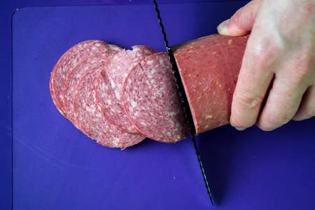 Slicing a sausage loaf with a black knife.の写真素材