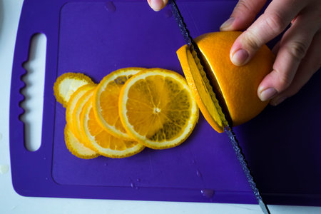 Sliced fruit is on the board with a black knife.