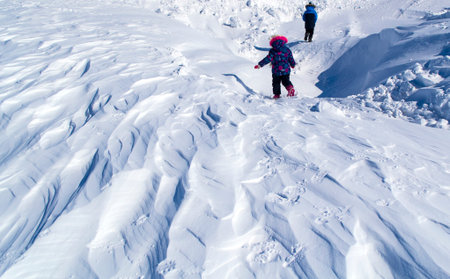 Relief on snow cover after a blizzard. Children go down the mountain.