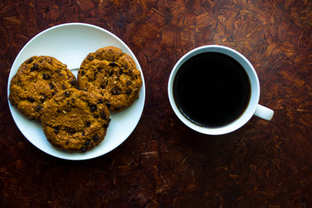 A cup of coffee and a round cookie on a saucer, morning breakfast.