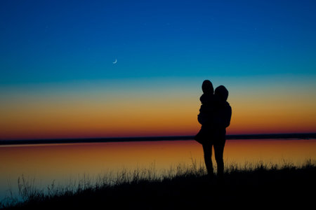 Mother and children hold hands in the background of the sunset.