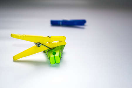 Colorful plastic clothespins on a light background. Space for your inscription. Minimalism, original and creative photography. Be different. The concept of individuality. Vertical wallpaper for a smartphone. High quality photoの写真素材