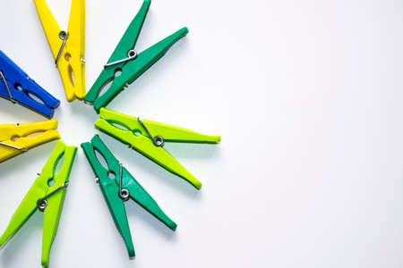Colorful plastic clothespins on a light background. Space for your inscription. Minimalism, original and creative photography. Be different. The concept of individuality. Vertical wallpaper for a smartphone. High quality photoの写真素材