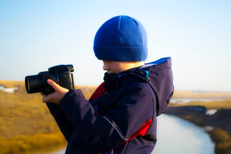 A boy holds a camera, filming the nature of the spring evening.