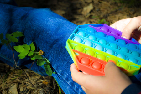 The boy is resting in the park, playing pop it, replacing the phone, outdoor activities.