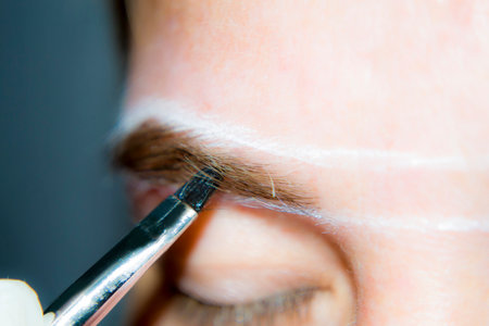 A girl undergoes eyebrow correction at the pandemic communications home. Home business.の写真素材