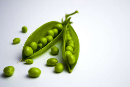 Green peas in pods on a white background, healthy vegetarian food.の写真素材