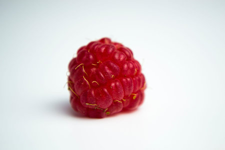 A closeup shot of fresh raspberries spread on a white background - perfect for a food blog