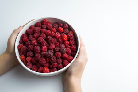 A close-up shot of a fresh raspberry in a white cup a child is holding in his hands - ideal for a...