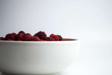 A close-up shot of a fresh raspberry in a white cup - perfect for a culinary blog diet and the benefits of natural vitamins. Healthy lifestyle. There is a place for your inscription.の写真素材