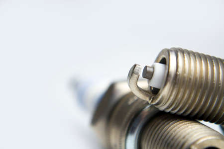 Creative abstract car repair service and automotive transportation industry business concept: macro view of metal spark plugs isolated on white background with reflection and selective focus effectの写真素材