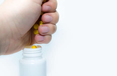 The hand falls asleep the pills in a white jar on a white background.の写真素材