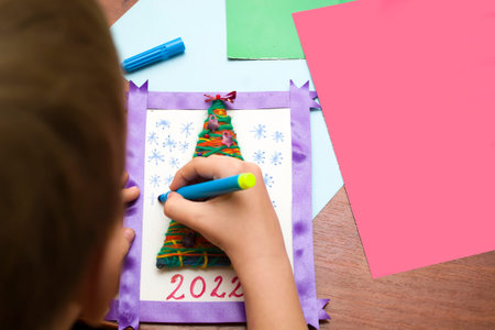 A child makes a Christmas card with his own hands.