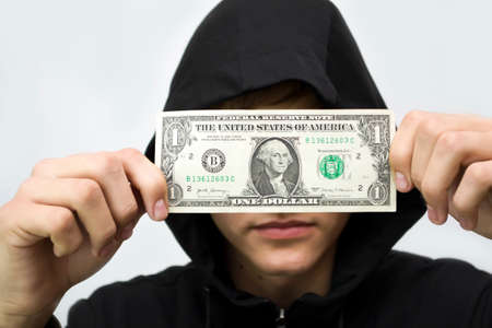 The guy in the hood holds the dollar covering his face on a white background.の写真素材