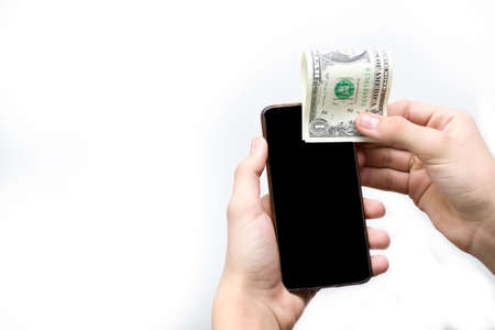 One dollar and a black phone in the hands of a teenager on a white background, affordable communication for one dollar.の写真素材